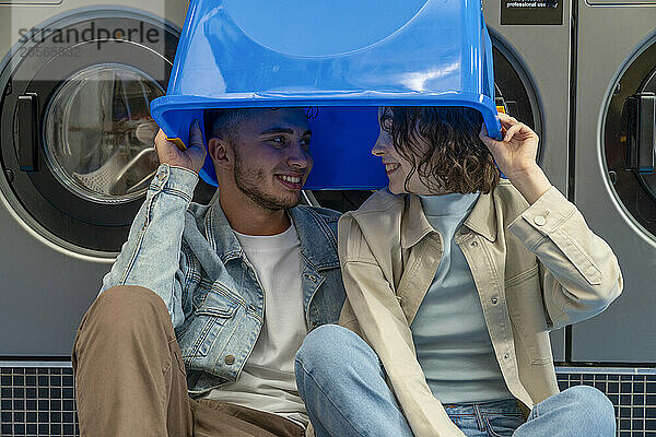 Smiling young couple looking at each other in blue laundry basket