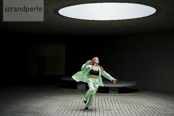 Happy redhead dancer under illuminated light