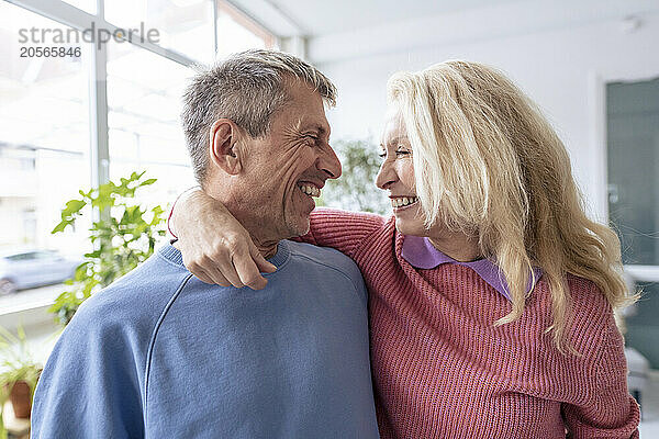 Cheerful blond senior woman with arm around looking face to face at man