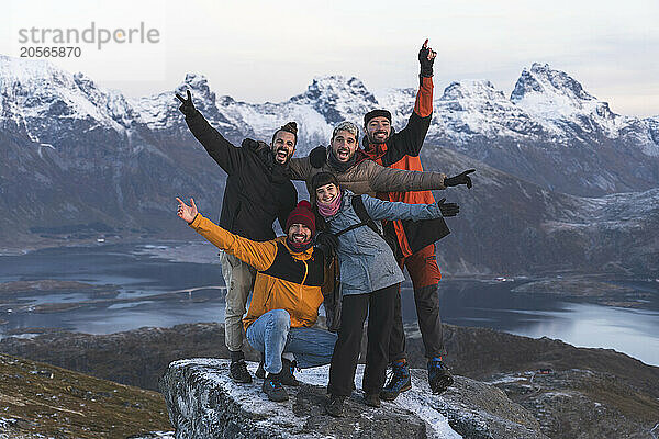 Cheerful friends standing on rock during winter at Lofoten islands