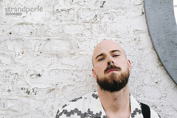 Bearded man near white brick wall