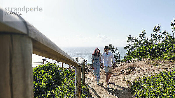 Boyfriend and girlfriend walking together near railing