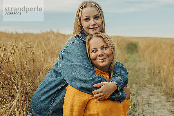 Young woman with arm around mother at wheat field