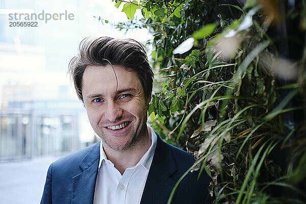 Smiling businessman near green plants