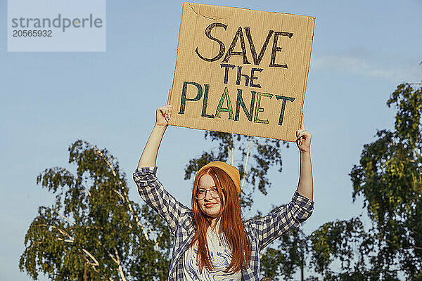 Redhead teenage girl in knit hat holding banner for protest