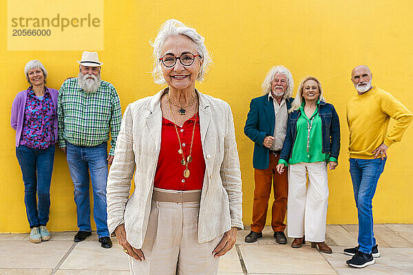 Smiling fashionable senior woman with friends in background