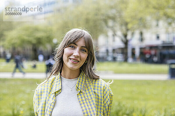 Smiling beautiful young woman wearing checked pattern shirt at park