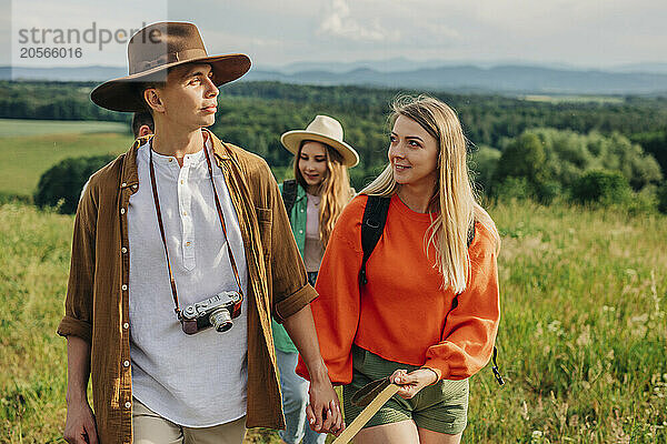 Young couple holding hands and hiking with friends on mountain in Poland