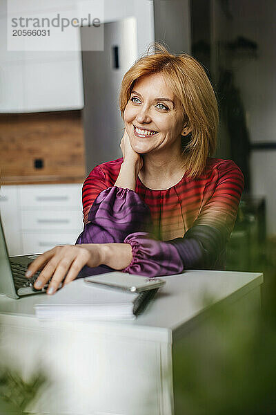 Smiling businesswoman with laptop in home office