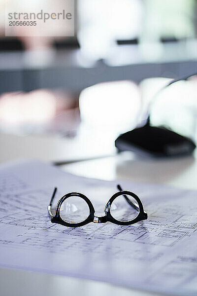 Eyeglasses on blueprint at desk in office