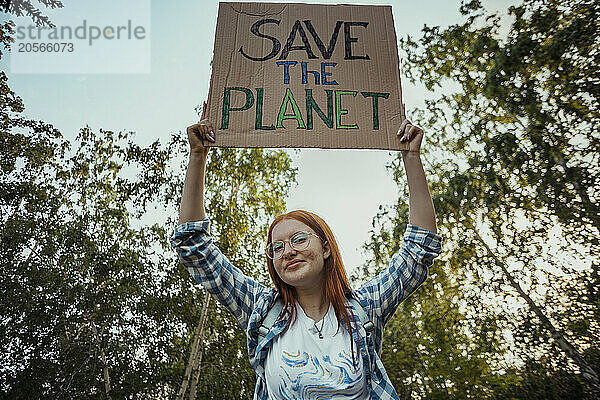 Teenage redhead girl holding protest banner at public park