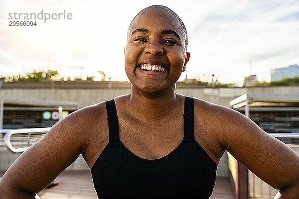 Happy muscular bald woman under sky