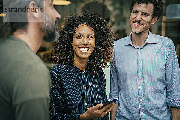 Business professionals holding smartphone near cafe