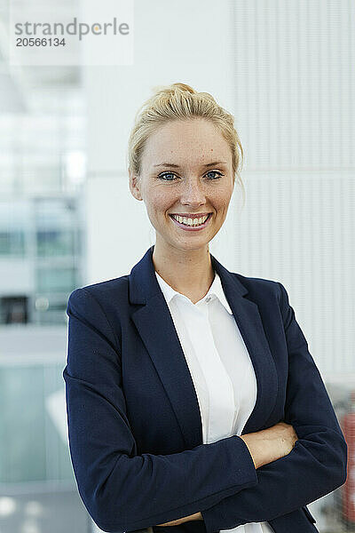 Happy businesswoman with arms crossed standing in airport