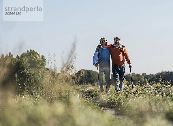 Friends with arm around walking at field