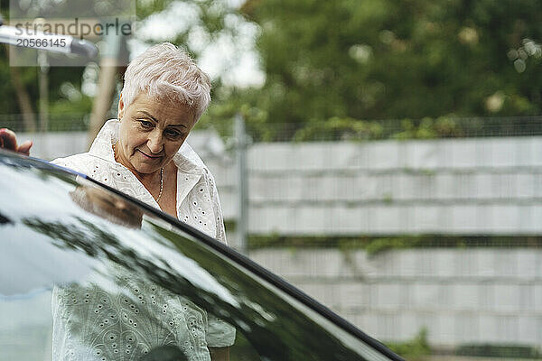 Senior woman examining electric car