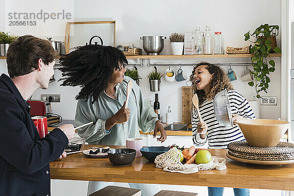 Happy family preparing food together singing and dancing in the kitchen