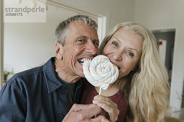 Happy senior couple eating candy lollipop