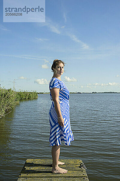 Mature woman standing on pier of Friesland lake in Netherlands