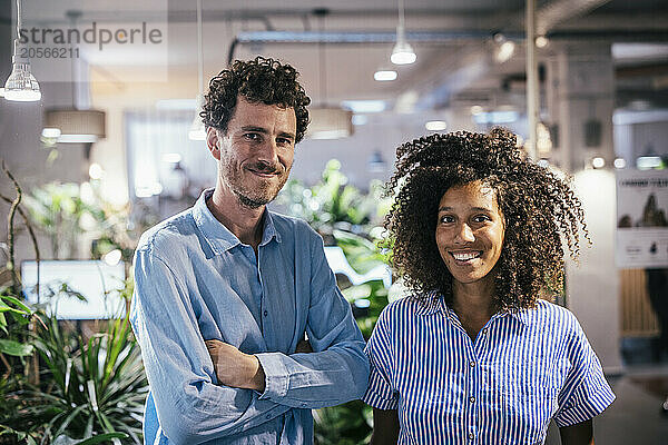 Smiling man with arms crossed standing with friend at cafe