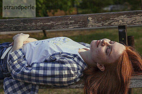 Carefree girl sleeping on bench at public park