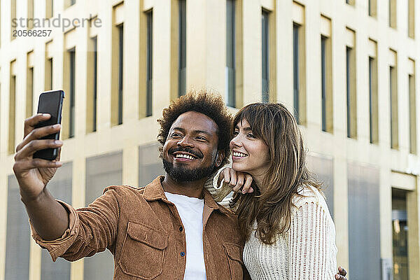 Happy man taking selfie with girlfriend in city