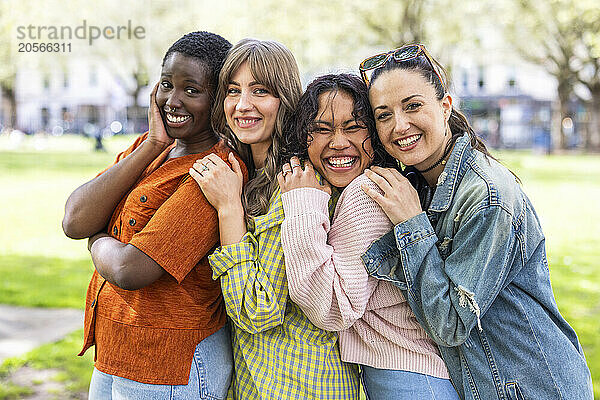 Cheerful multiracial women leaning on each other at park