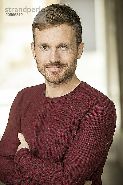 Man with arms crossed and wearing maroon sweater