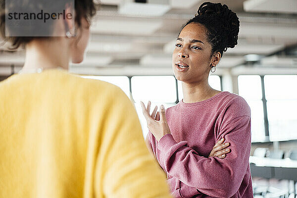 Confident young businesswoman discussing with colleague at office