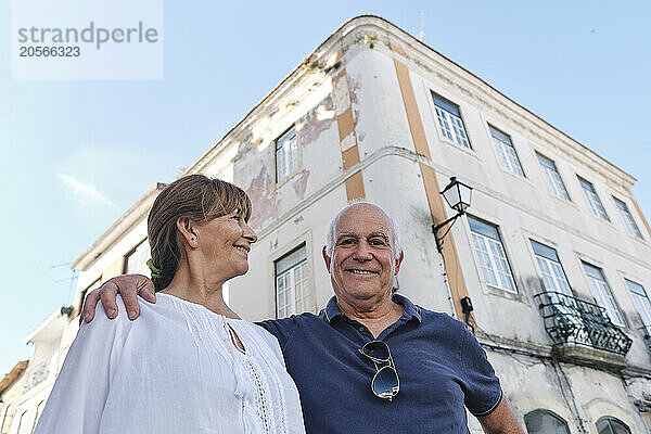 Smiling senior woman with man standing in front of buildings