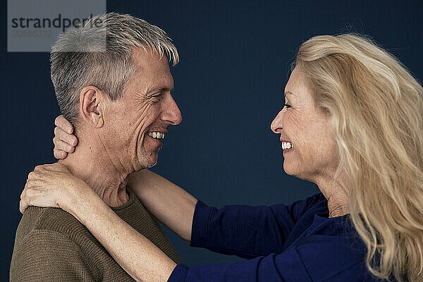 Happy retired loving senior woman face to face with man against blue background