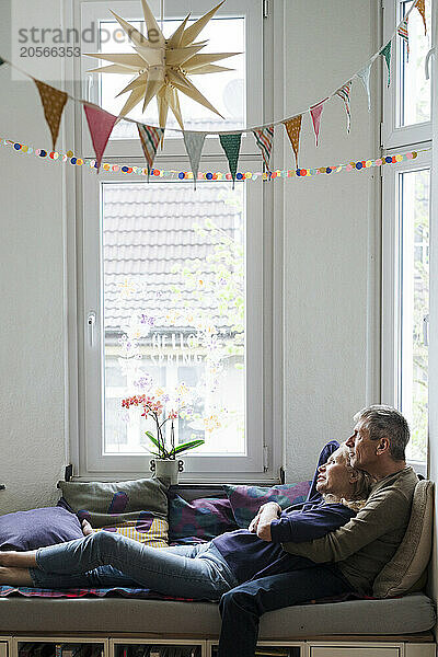 Retired senior couple relaxing on alcove window seat at home