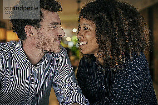 Smiling man and woman looking at each other sitting in cafe