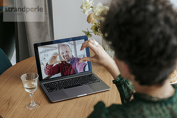 Couple making heart shape gesture on video call at home