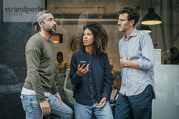 Business professionals talking with colleague near cafe