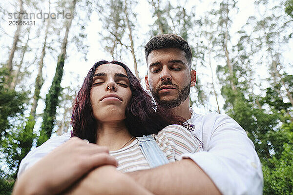 Boyfriend and girlfriend with eyes closed in forest