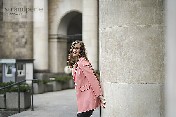 Happy young woman standing near pillar of Palace of Culture and Science