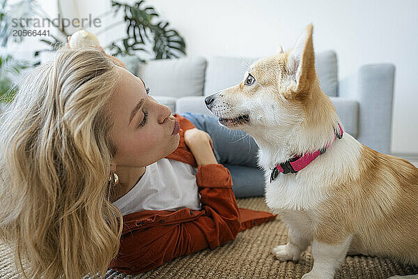 Blond woman kissing dog at home