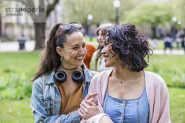 Happy women talking and walking with arm in arm at park