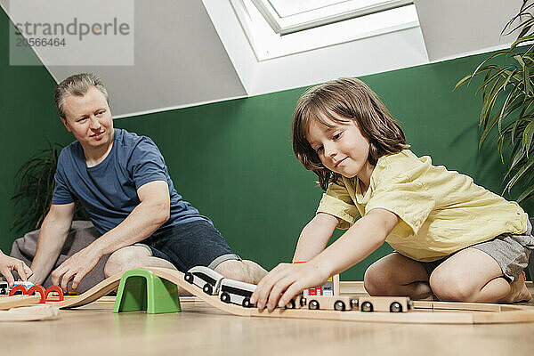 Cute boy playing with train toy with father and spending leisure time at home