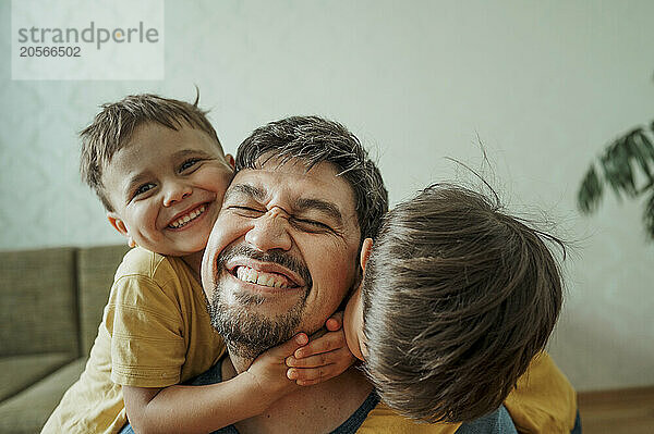 Cheerful boys having fun with father at home