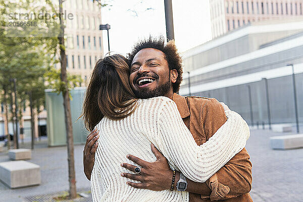 Happy man with eyes closed embracing girlfriend