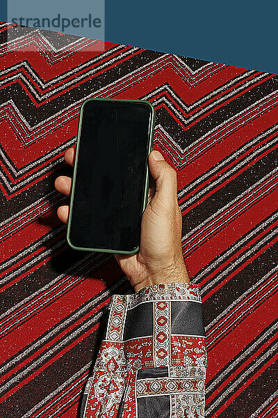 Hand of man holding smart phone against abstract background