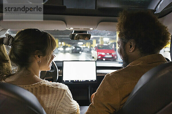 Smiling man and woman sitting in car