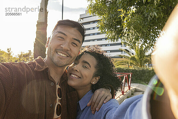 Smiling young couple taking selfie at park