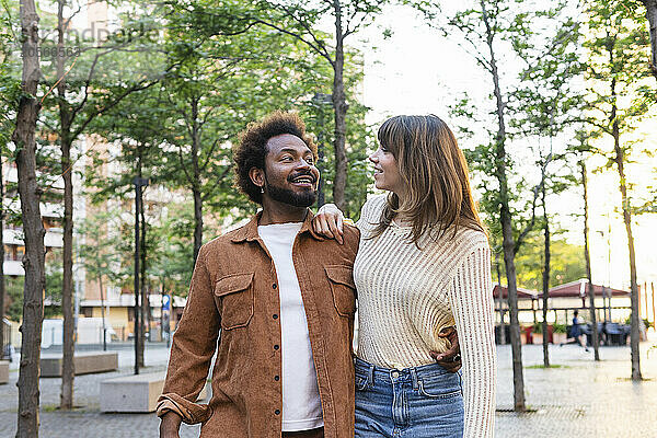 Smiling man and woman walking with arms around