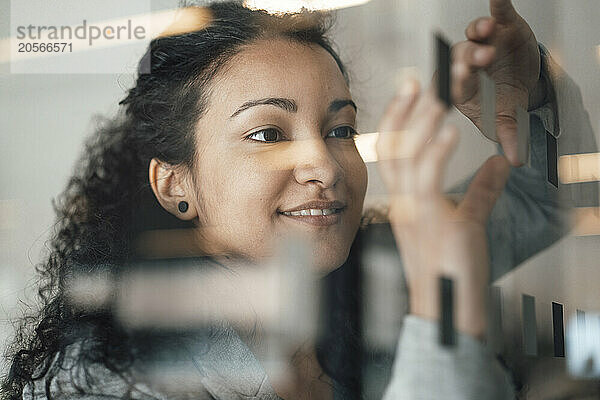 Businesswoman with curly hair touching glass wall