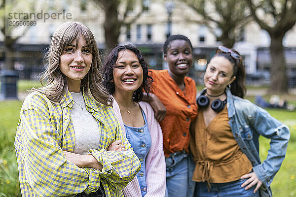 Smiling multiracial female friends standing together at park