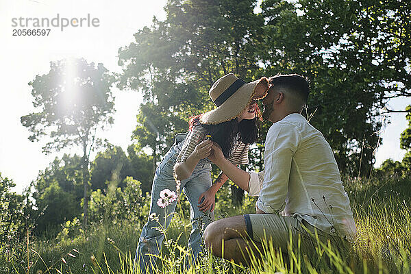 Woman kissing boyfriend in park at sunny day