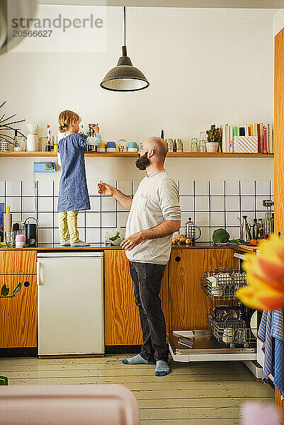 Father near daughter standing on kitchen counter at home